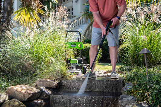 A man using a Greenworks pressure washer to clean steps.