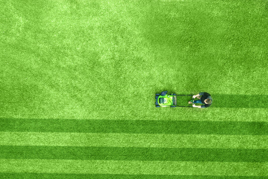 A man using a Greenworks lawn mower to cut grass
